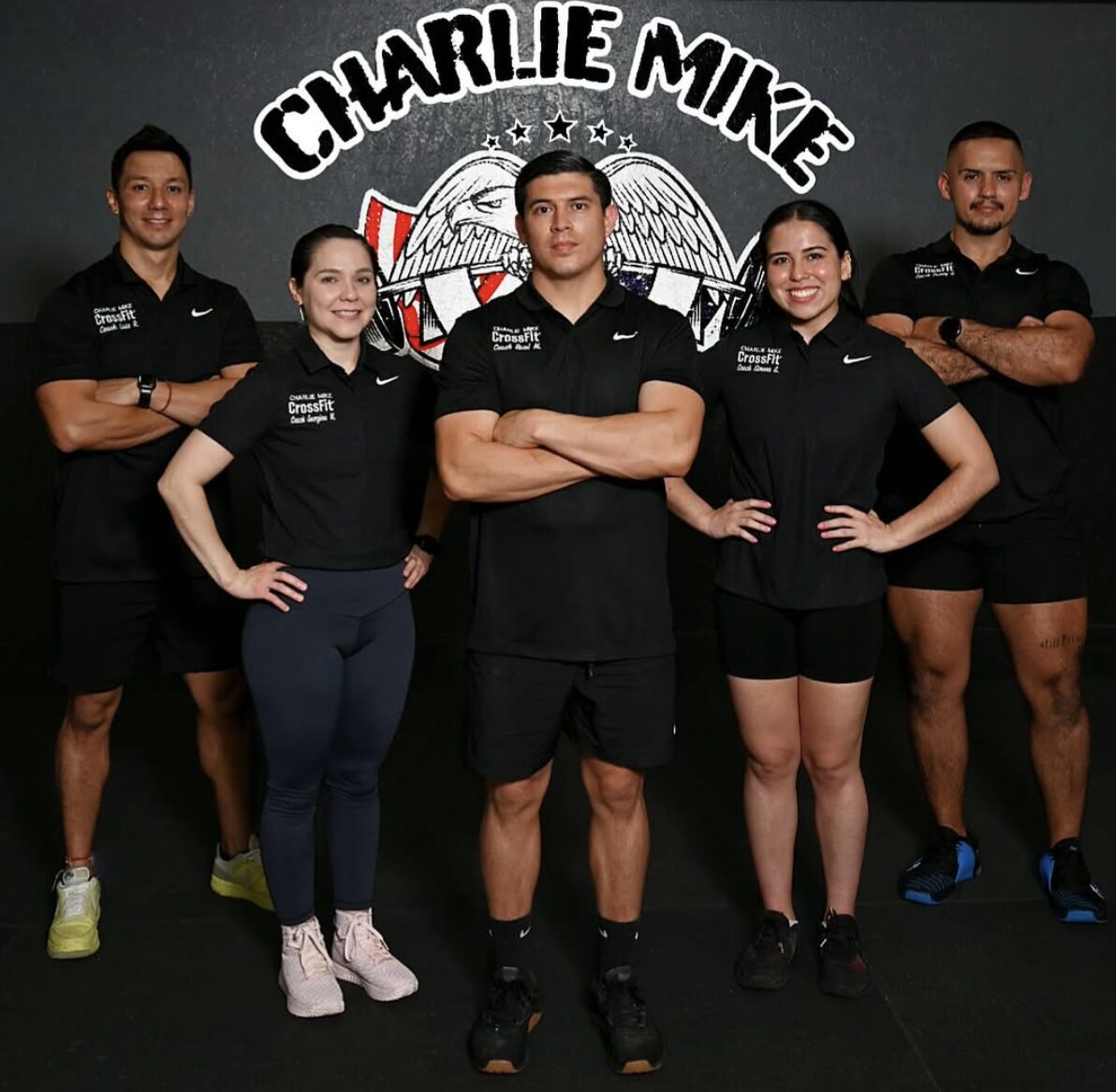 The Charlie Mike CrossFit coaching staff in front of the gym crest
