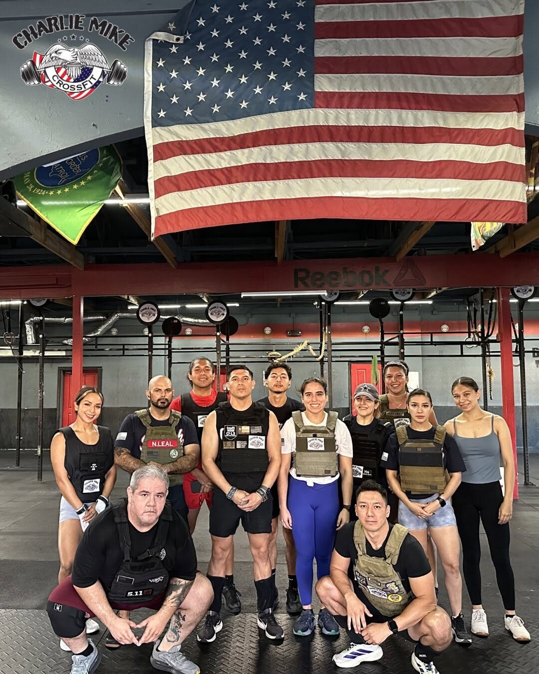 Members in weighted vests under the flag before a hero workout